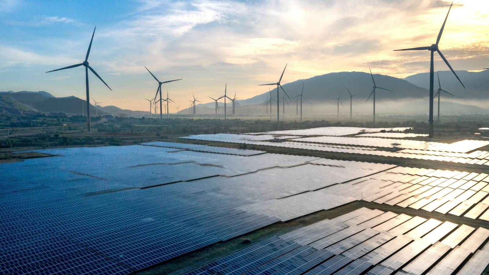** Weites Feld von Solarmodulen im Hintergrund, im Vordergrund ein kleiner Silberbarren in unscharfer Nahaufnahme