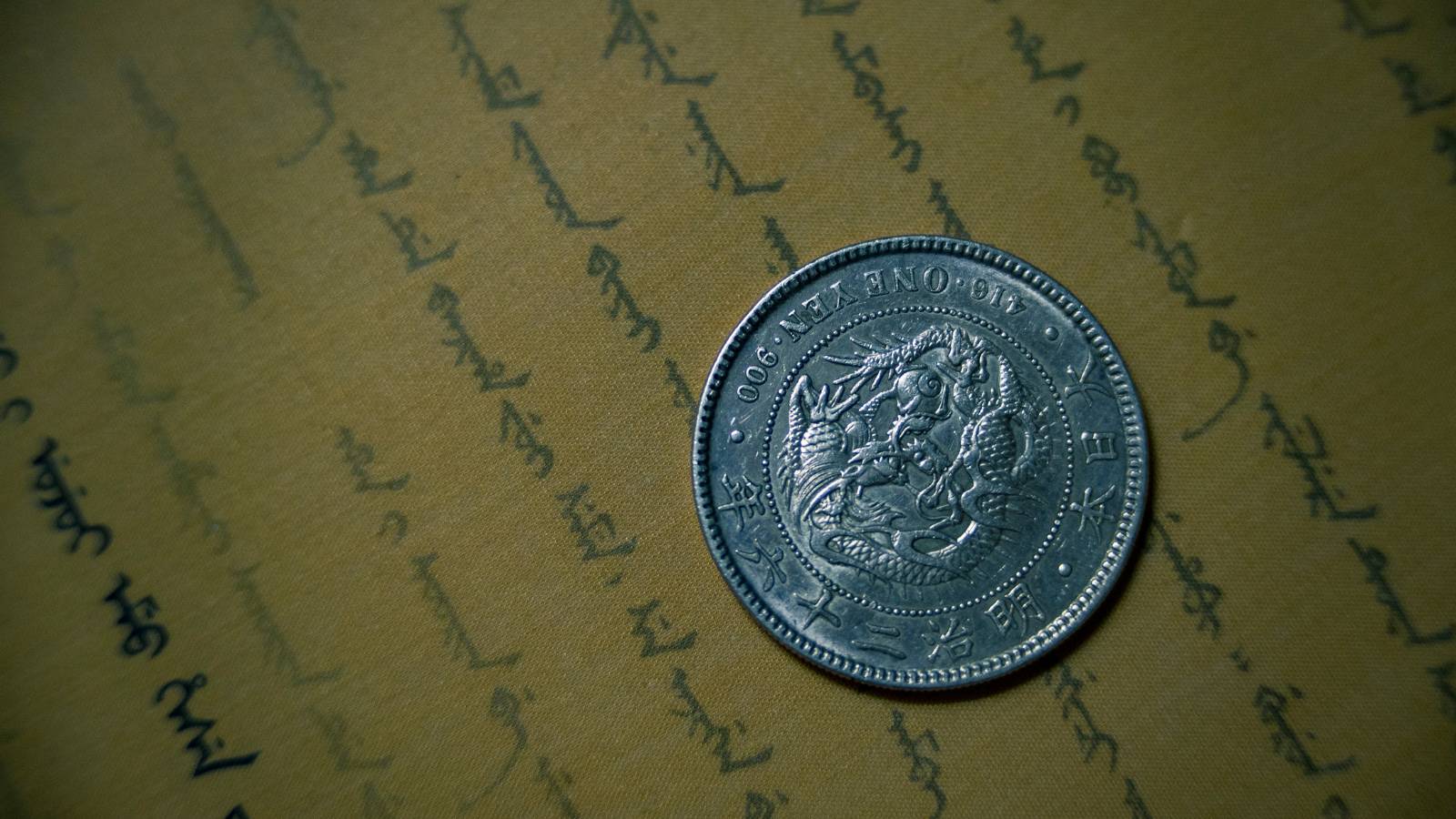 Silbermünze und ein rechnungsähnliches Dokument nebeneinander auf einem Tisch, in klarer Komposition